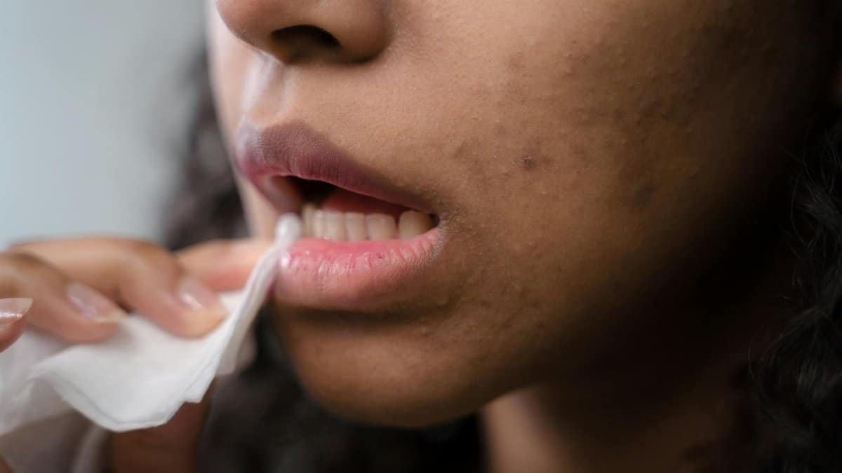 Detailed close-up of a woman wiping her lips, showing skin texture and care.