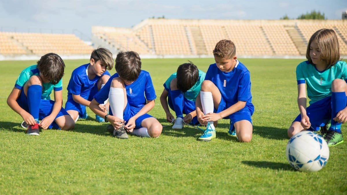 Group of young soccer players putting on shoes in a stadium in Portugal.