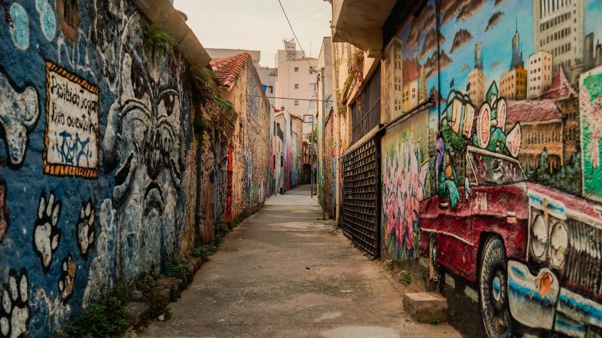 Explore a colorful alleyway adorned with vibrant street art and graffiti in an urban setting.