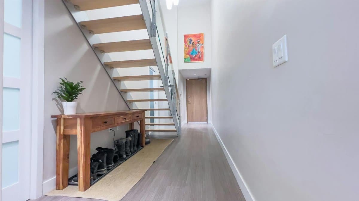 Bright and airy hallway with wooden staircase in a minimalist modern home, showcasing simplicity and elegance.