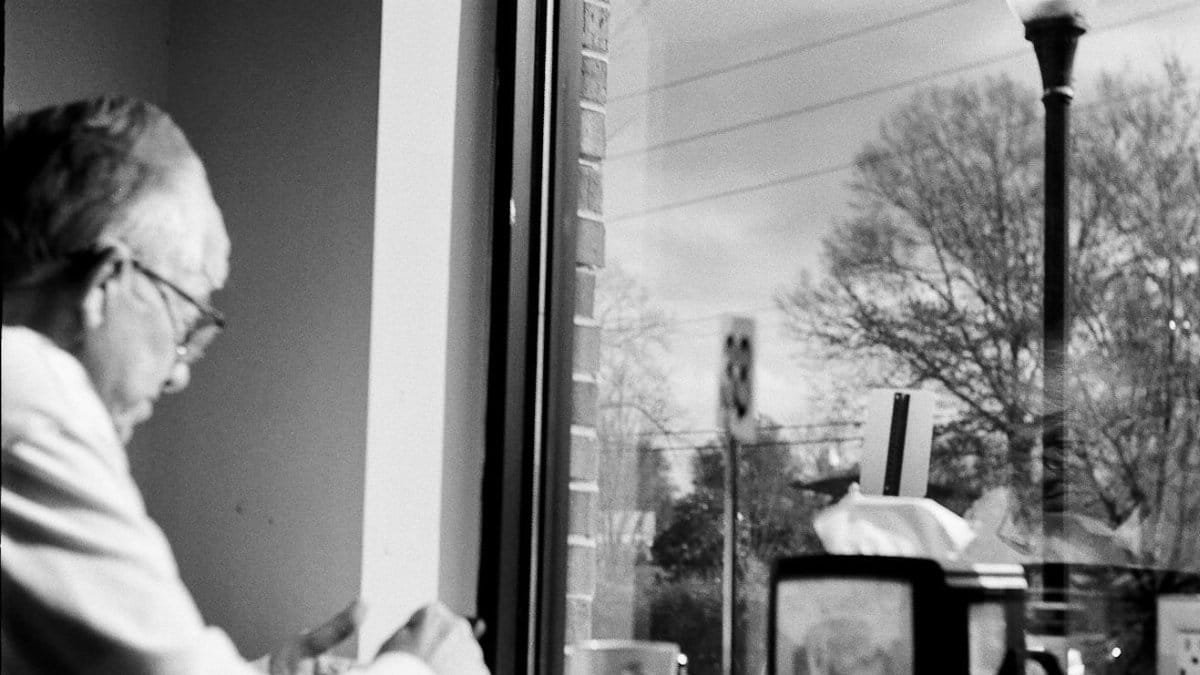 Black and white image of a man sitting alone in an urban café, Kennesaw.