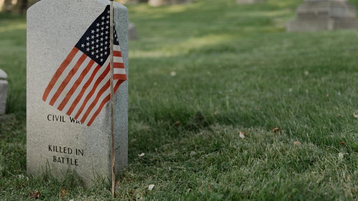A gravestone with an American flag in a cemetery, honoring a civil war veteran.