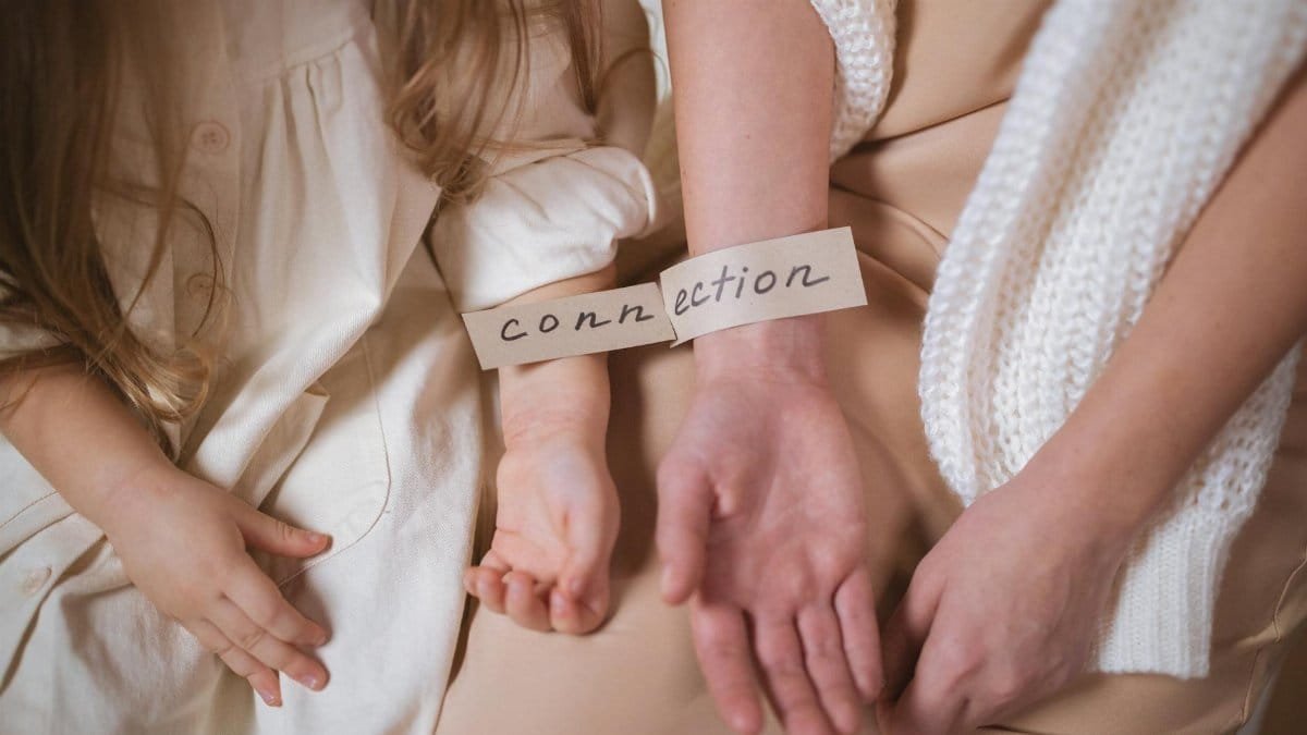 A mother and child showcasing the theme of connection with a label on their wrists.