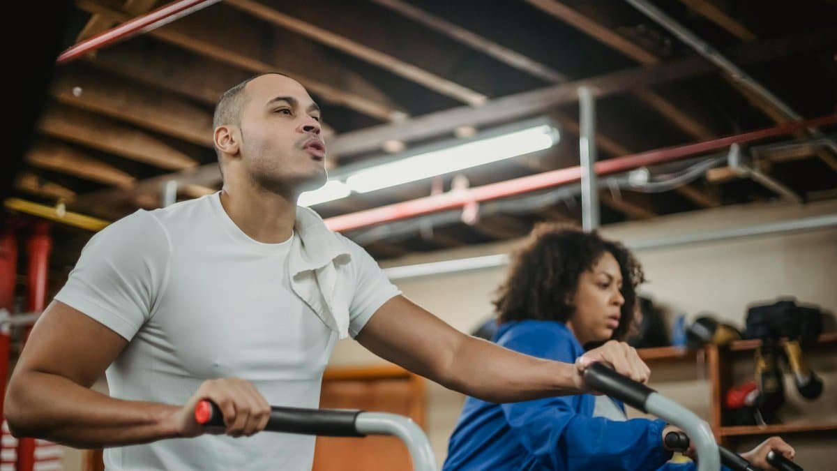 Focused gym session with diverse trainers cycling energetically indoors.