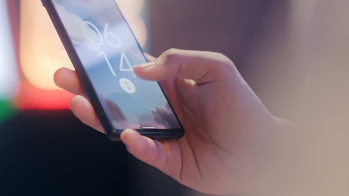 Close-up of a hand holding a smartphone locked with a fingerprint sensor.