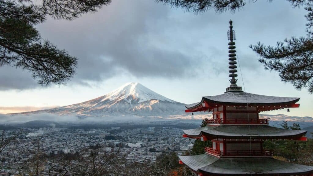 Scenic view of Chureito Pagoda with snow-capped Mount Fuji under a cloudy sky in Fujinomiya, Japan.