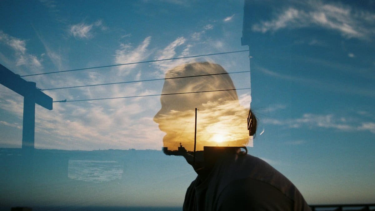 Artistic double exposure of a silhouette with a scenic sky background, blending nature and human form.