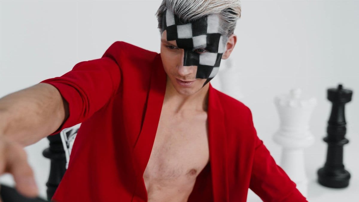 Expressive portrait featuring a man with chess-themed face paint and bold fashion, merging strategy with style.