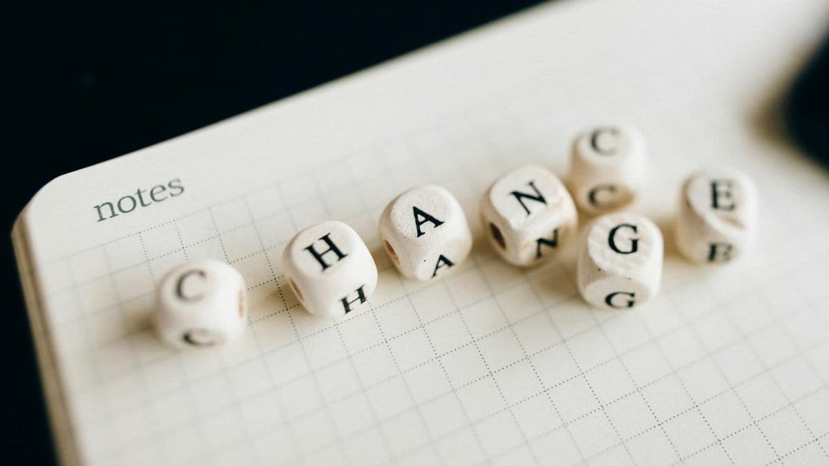 Close-up of letter dice spelling 'change' on a grid notepad, symbolizing transformation.