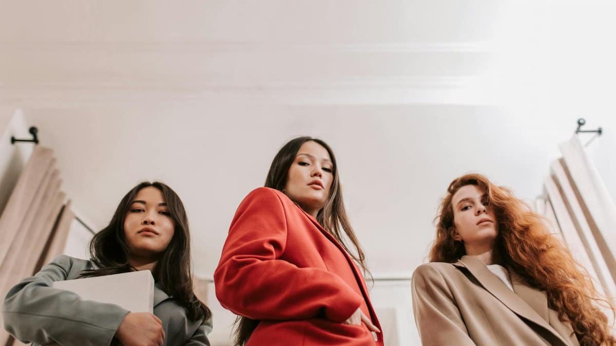 Three confident businesswomen in blazers pose in a low angle shot, embodying leadership and empowerment.