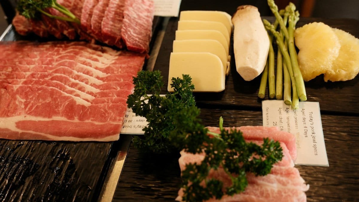 A gourmet platter featuring sliced meats, cheese, mushrooms, asparagus, and parsley.