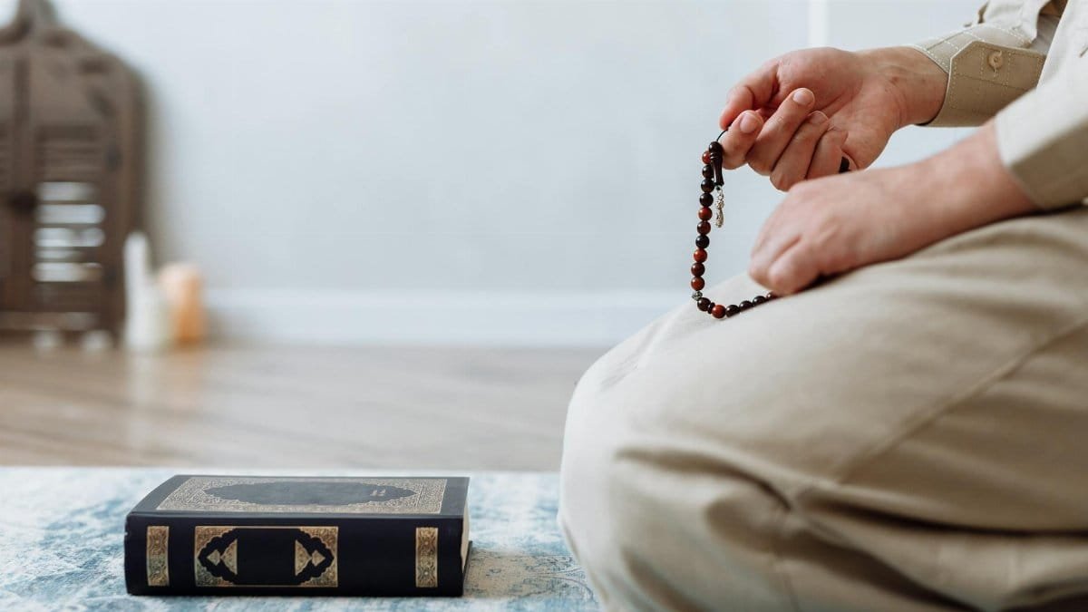 A close-up shot of a person holding prayer beads next to a Quran, illustrating faith and meditation.