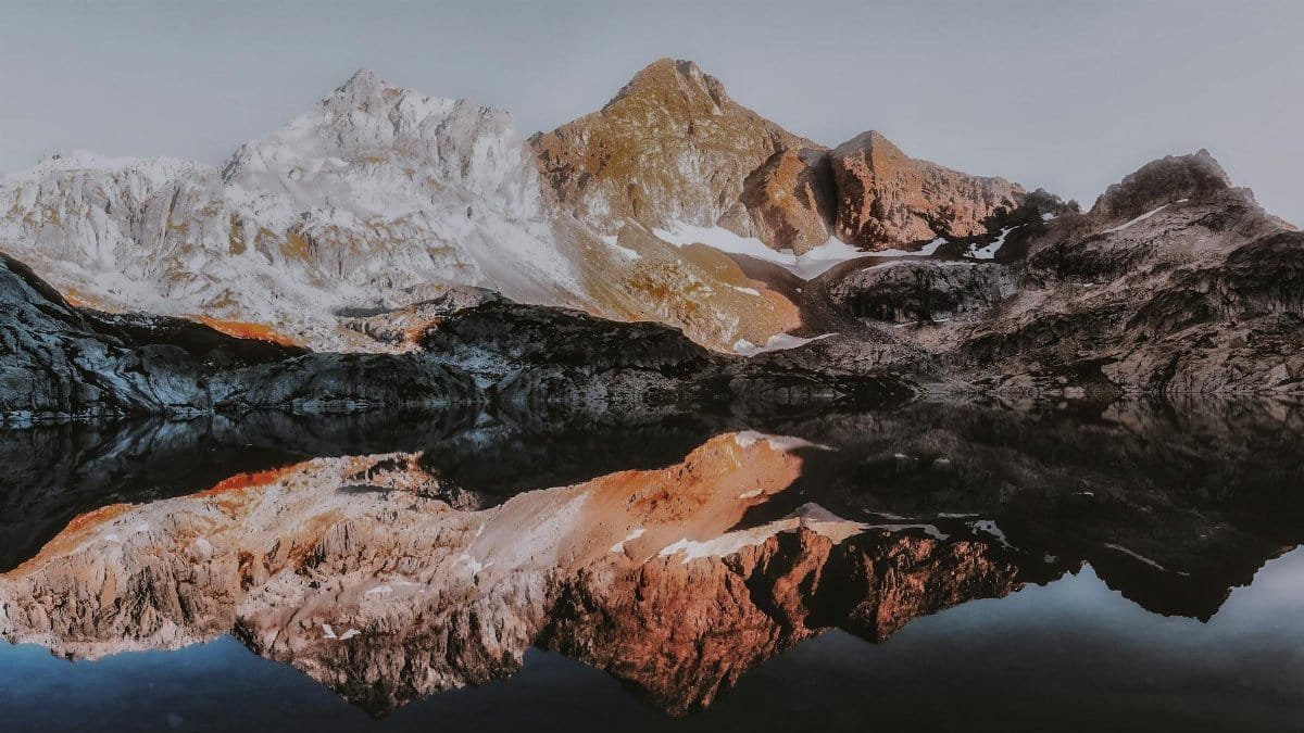 Stunning mountain landscape with snow-capped peaks reflecting in a calm lake, showcasing nature's serenity.