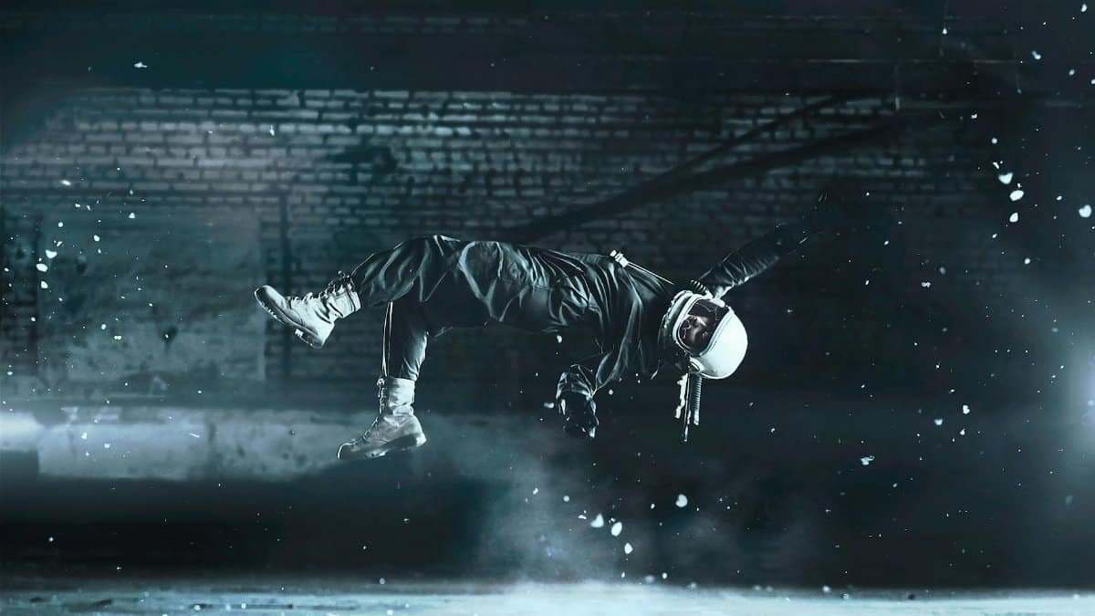 A cosmonaut floats effortlessly in an artistic fashion amidst a dimly lit indoor space.