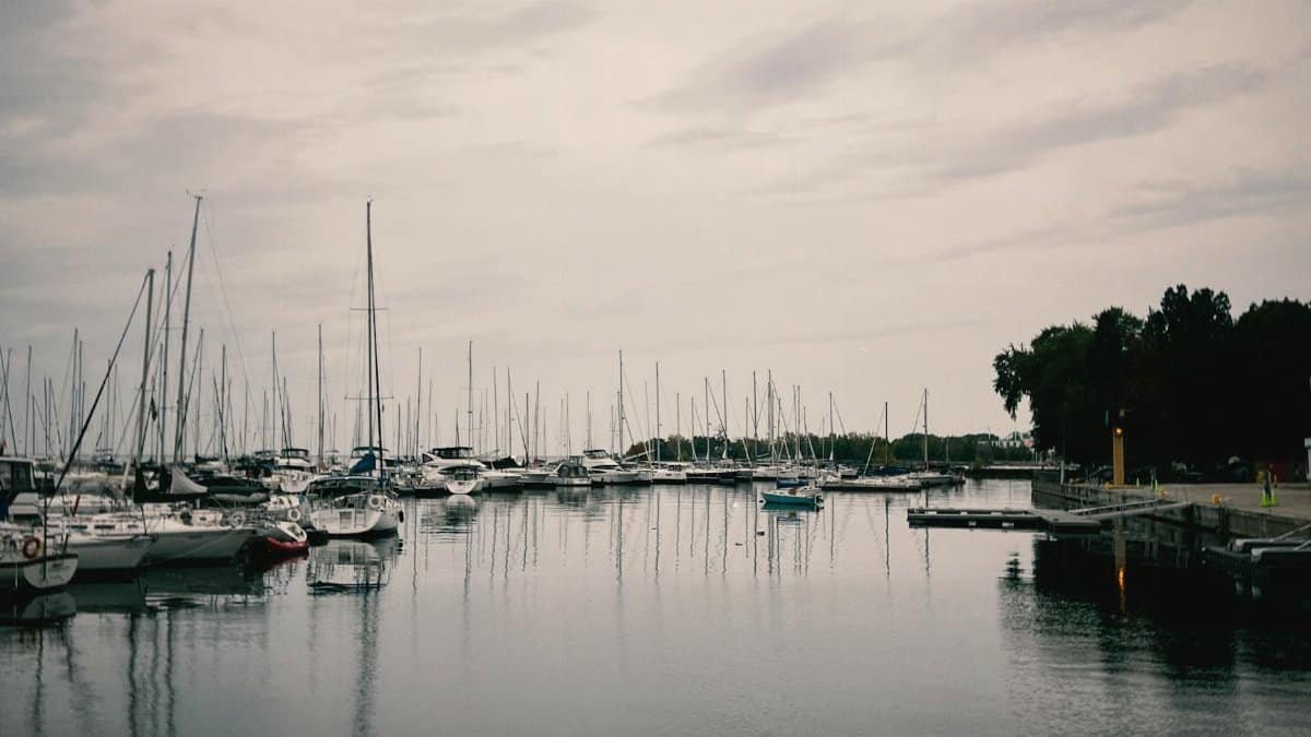 A tranquil marina scene with boats and clear water reflections at sunset.