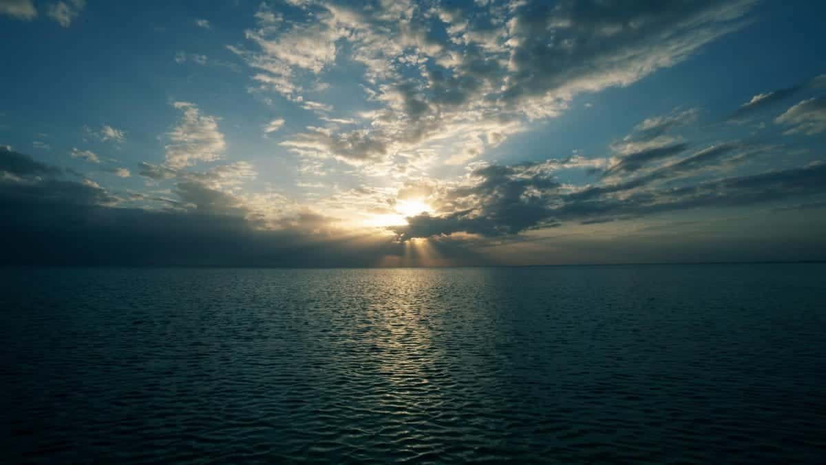 Captivating sunset over the ocean with dramatic clouds and rippling water, showcasing nature's serene beauty.