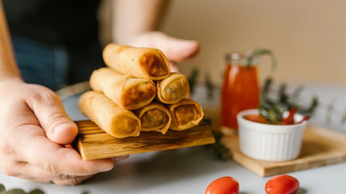 Close-up of crispy spring rolls served with dipping sauce and garnishes.