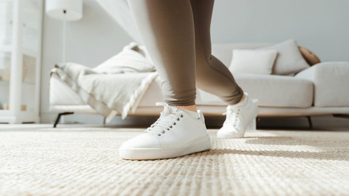 Close-up of a woman stretching in activewear at home, promoting wellness and fitness.