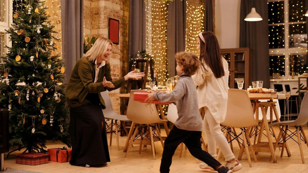 Joyful family celebrating Christmas with gift exchange indoors.