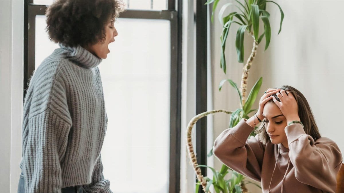 A heated argument between two women in a sunlit room, expressing disagreement and frustration.