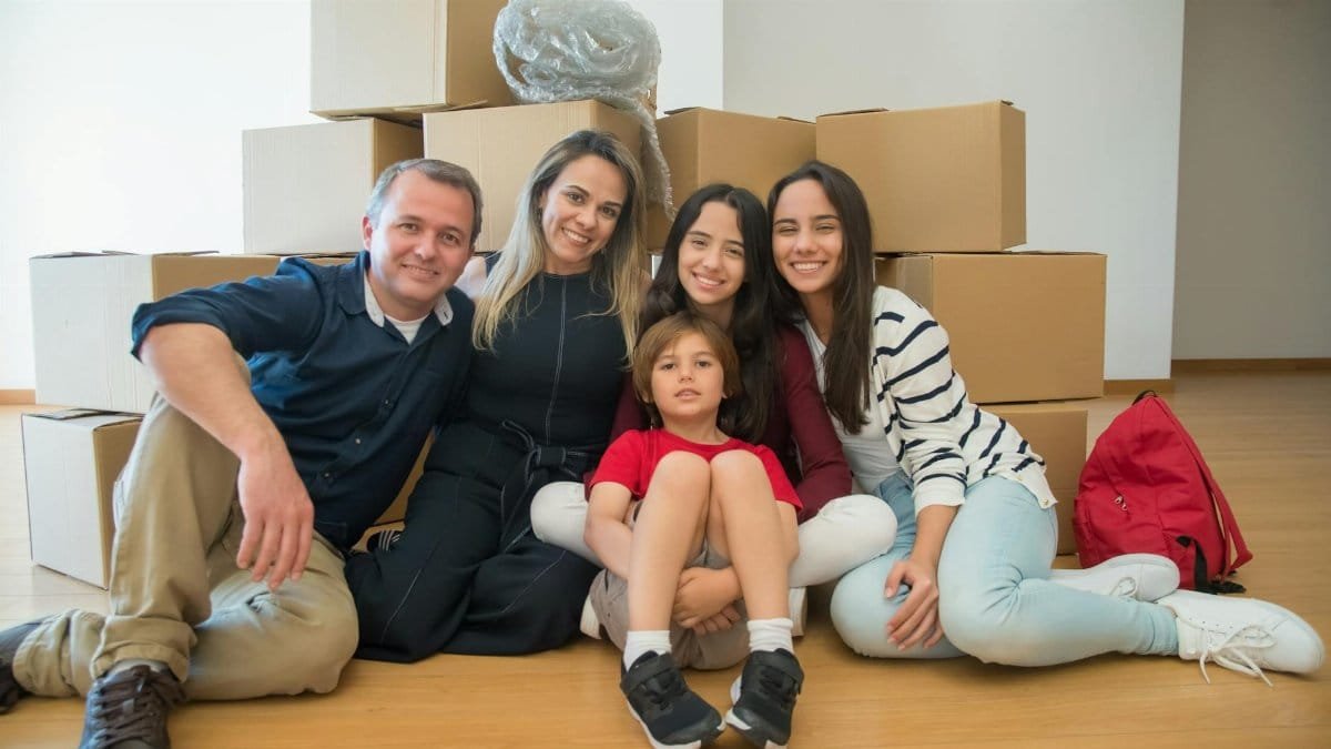 A joyful family sitting together with moving boxes in their new home.