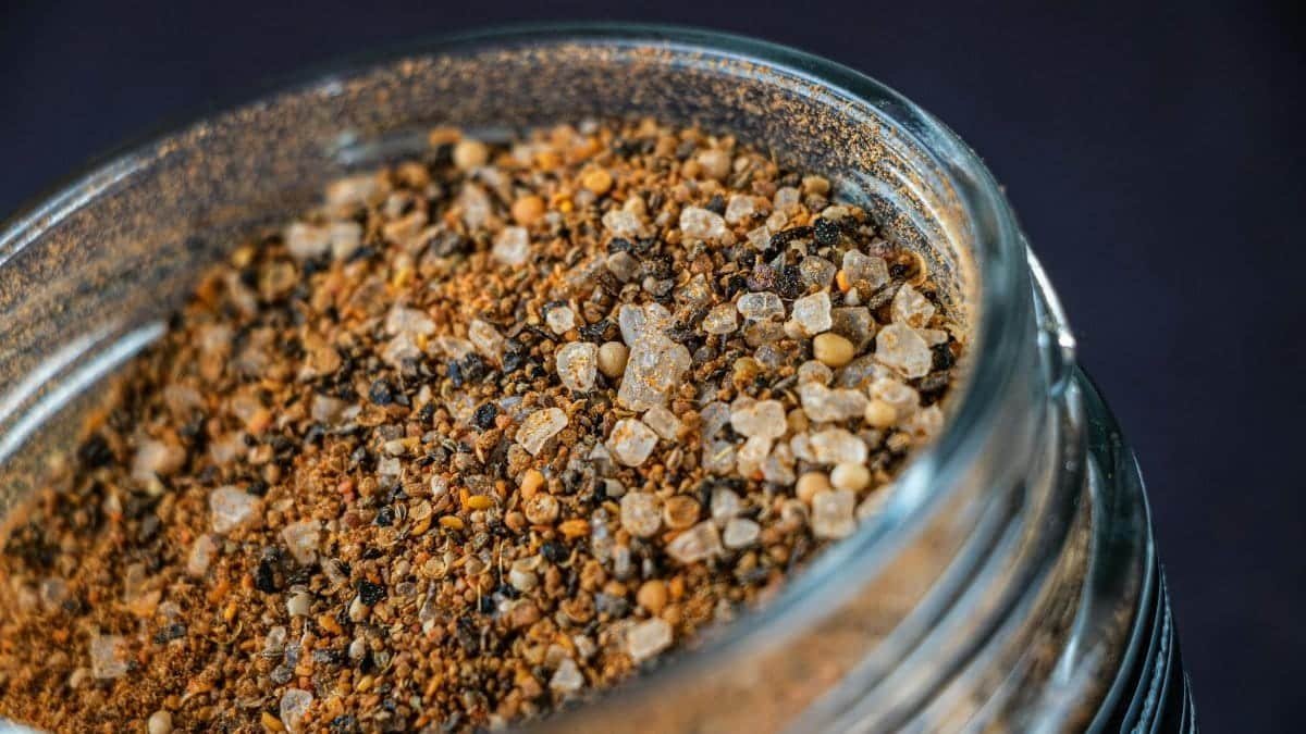 A detailed close-up of a spice mix in a glass jar, showcasing texture and color.