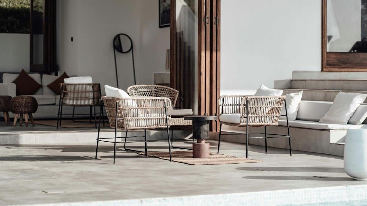 Luxurious outdoor seating area by the pool with modern wicker chairs and soft cushions.
