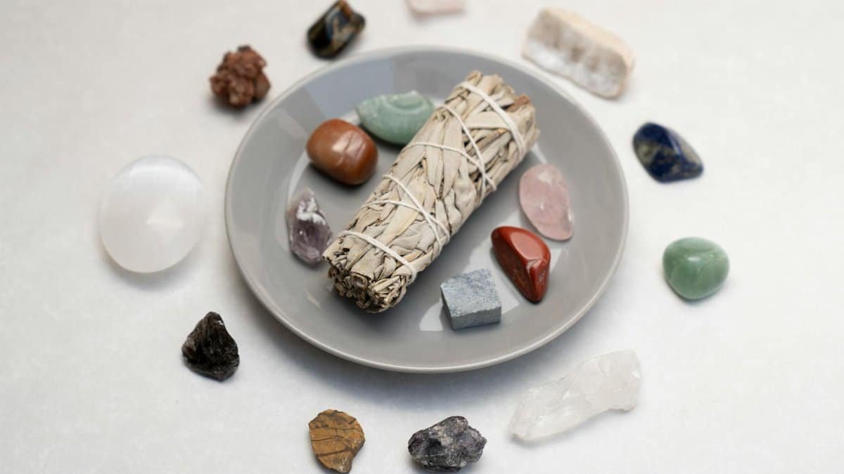 Ceramic plate with sage smudge stick and healing crystals for spiritual rituals.