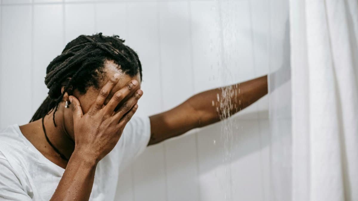 Young man experiencing emotional stress while in the shower, depicting mental health challenges.
