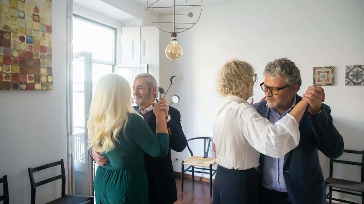 Two senior couples delight in dancing indoors, capturing a joyful and social moment.