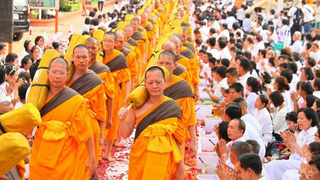 Vibrant procession of Buddhist monks and community in traditional Thai ceremony, Bangkok.