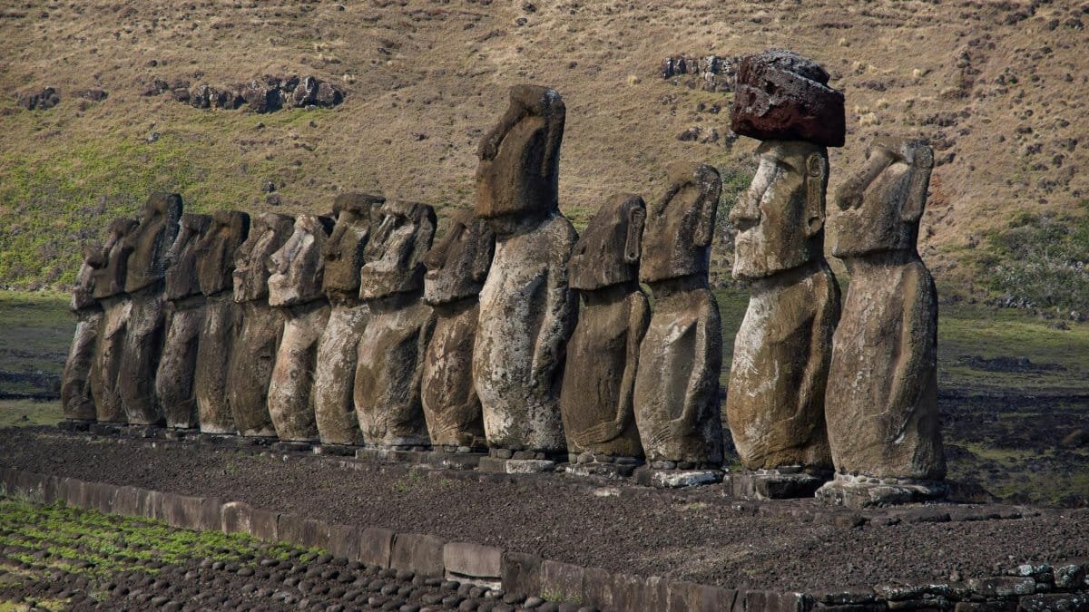 Majestic row of Moai statues on Easter Island under a bright sky.
