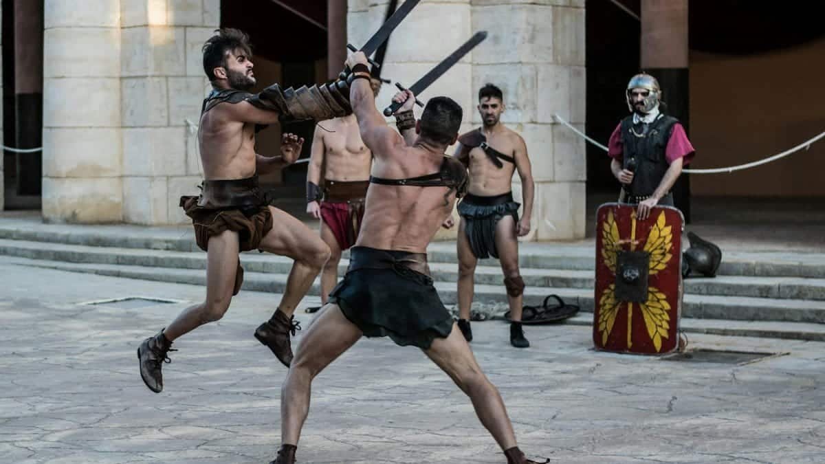 Intense scene of gladiators engaging in combat with swords in an ancient-style arena.
