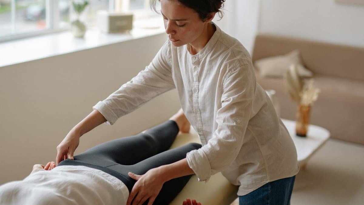 A massage therapist provides care to a lying patient in a tranquil indoor setting.