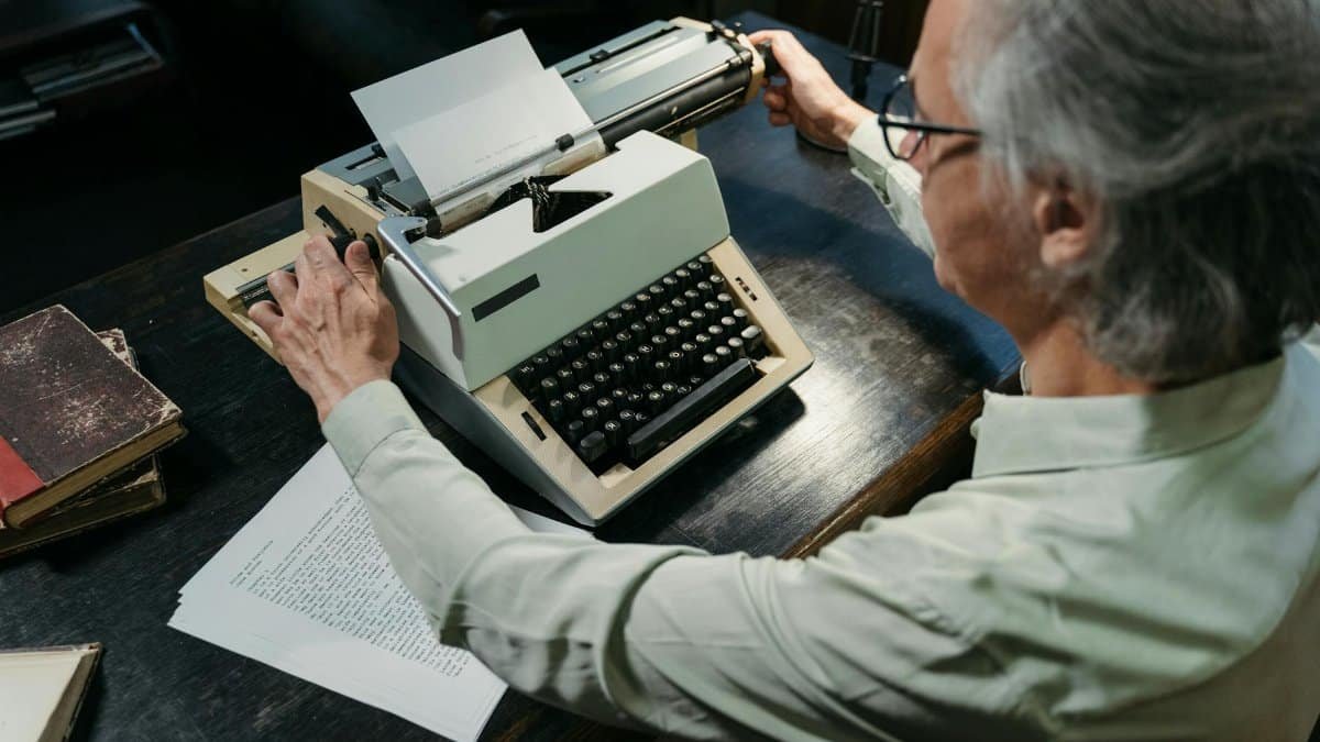 An adult man using a vintage typewriter in an office setting, capturing a timeless moment.