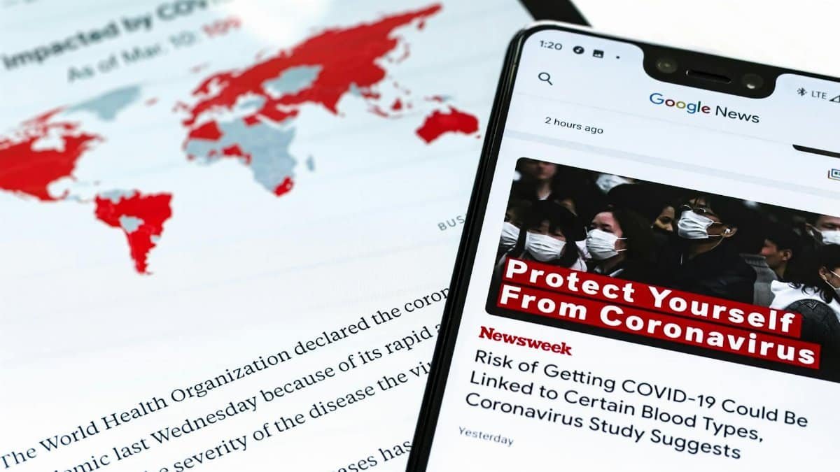 Smartphone with coronavirus updates and world map showing the impact of COVID-19.