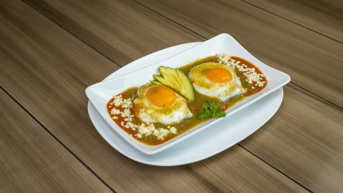 Delicious Huevos Rancheros on a plate with avocado slices in a Mexican restaurant setting.