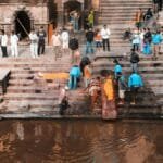 People attending a traditional funeral ceremony by a riverside in Nepal with cultural rituals.