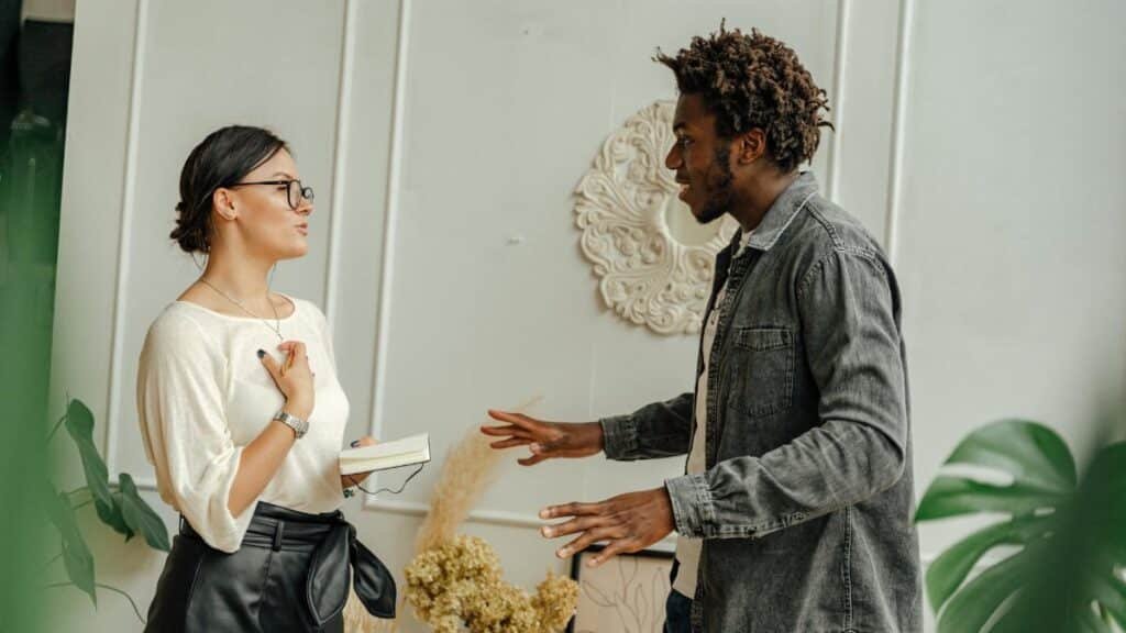 Two adults engaging in a friendly conversation indoors, sharing ideas.