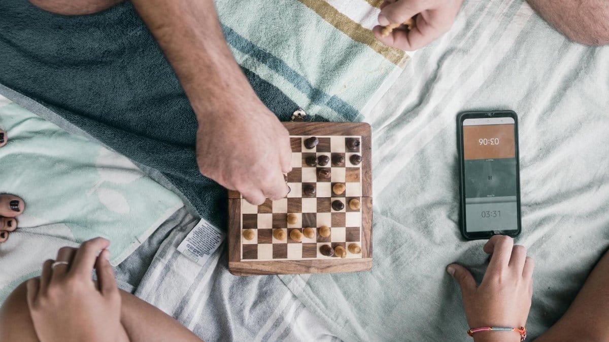 Casual indoor chess game with friends using a smartphone timer, showcasing strategic play and connection.