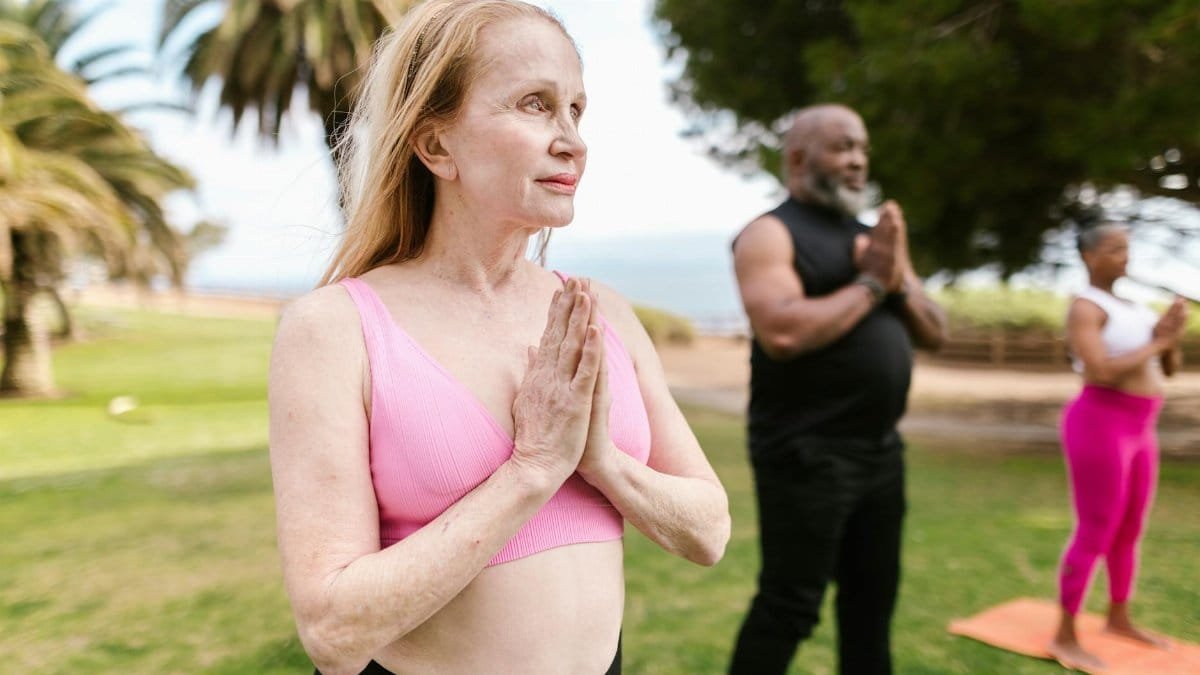 A group of senior adults practicing yoga in a serene park setting, promoting wellness.