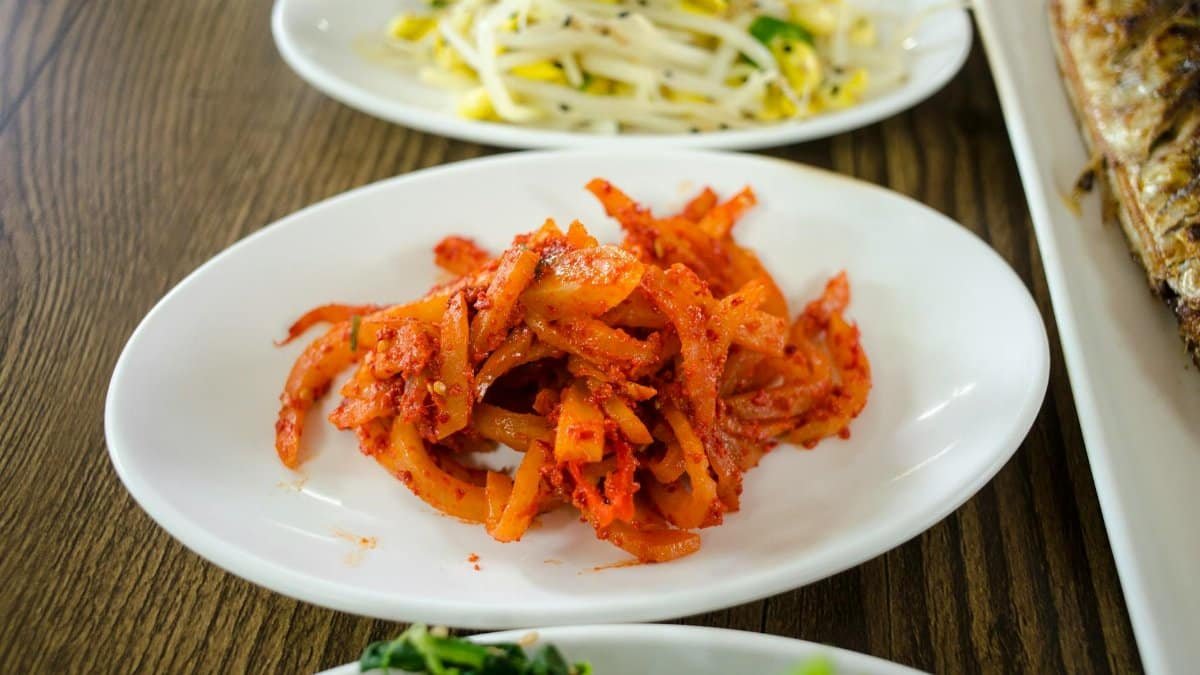 A vibrant collection of Korean side dishes featuring spicy kimchi, fresh greens, and bean sprouts.