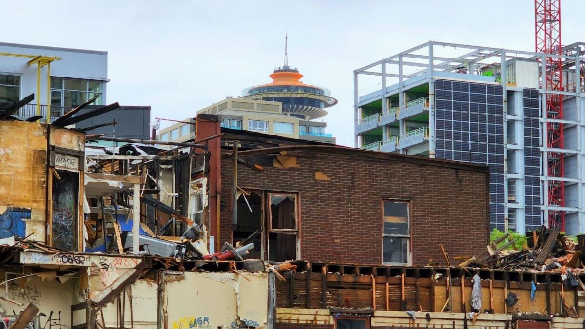 An urban demolition site with a mix of old and modern architecture in the background.
