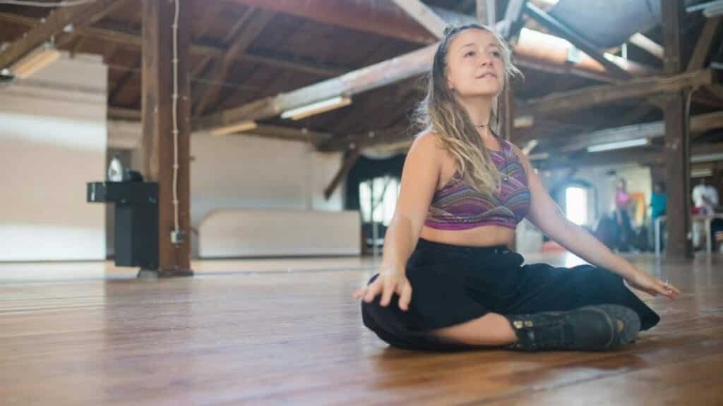 Caucasian woman meditating on a wooden floor in a rustic studio. Calm and peaceful environment.