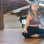 Caucasian woman meditating on a wooden floor in a rustic studio. Calm and peaceful environment.