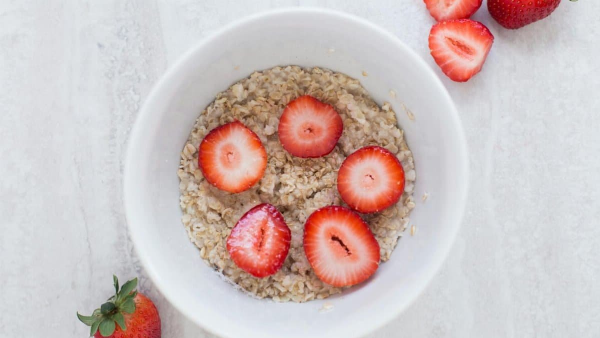A fresh and nutritious breakfast bowl featuring oats topped with sliced strawberries.