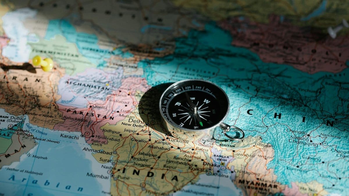 Close-up image of compass on a world map highlighting travel direction and exploration.