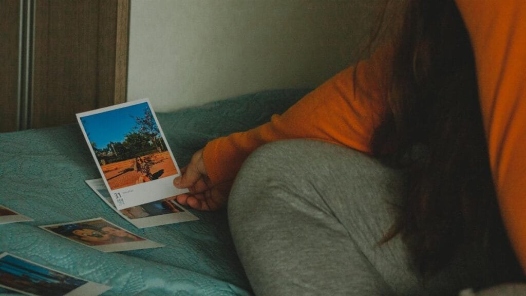 A woman in casual clothing reviews instant photos during a peaceful moment.