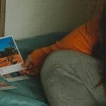 A woman in casual clothing reviews instant photos during a peaceful moment.