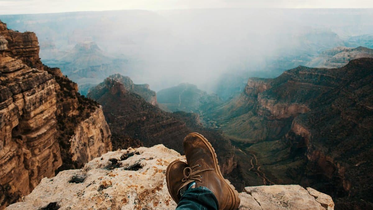 Brown boots on a rocky perch overlooking the vast Grand Canyon landscape.